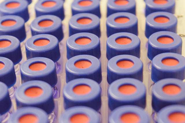 Close up of many gas chromatograph vials with blue and red lids