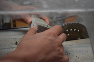 Person cutting a small piece of building material on a saw