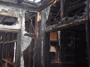 Badly fire-damaged walls and ceilings that only show the timber framing of a house after a fire