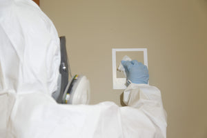 Person in white hazmat suit taking a swab sample for IANZ accredited meth test in a house